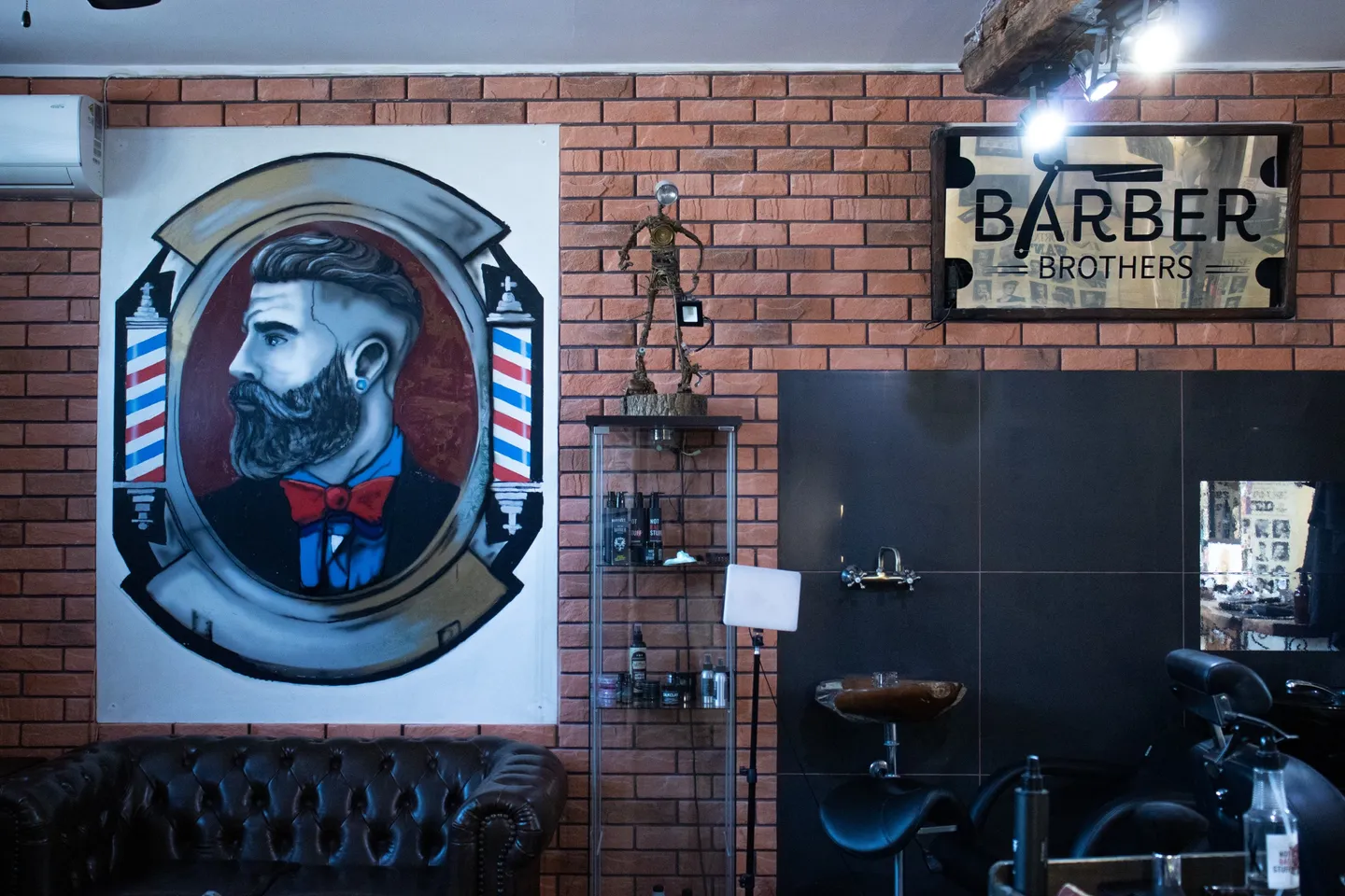 Wnętrze salonu Barber Brothers: mural barbera i szyld na ceglanej ścianie